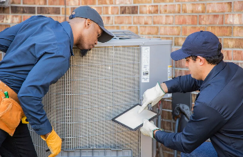 Two technicians inspect an air conditioning unit.