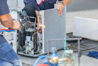 Two workers repair an air conditioner.