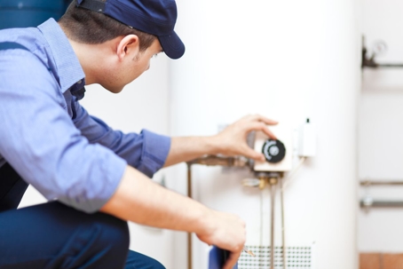 A technician adjusts a hot water heater.