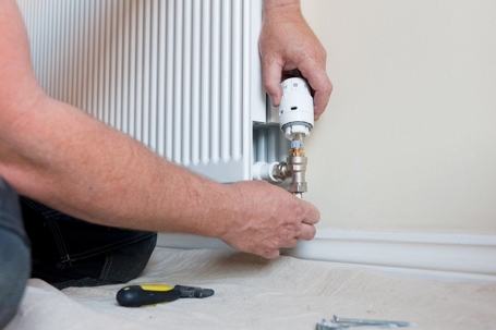 A person is installing a thermostat
